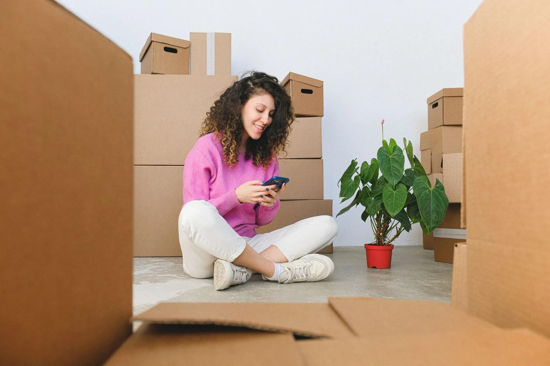 cliente qui suit son déménagement sur son téléphone au milieu des cartons